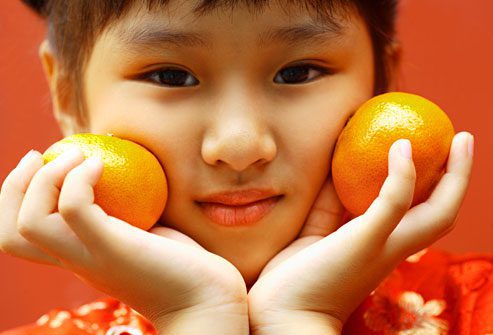 asian kid with two oranges